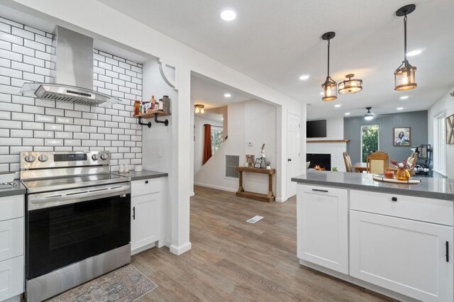 kitchen featuring stainless steel electric range oven, white cabinetry, and wall chimney exhaust hood