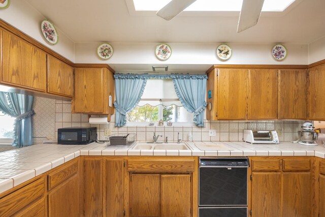 kitchen featuring black appliances, plenty of natural light, backsplash, and tile counters