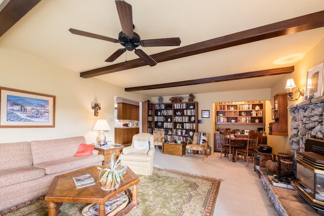 carpeted living room with a fireplace, beam ceiling, and ceiling fan