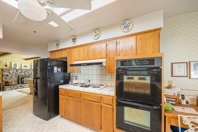 kitchen with ceiling fan, tile counters, light colored carpet, and black appliances