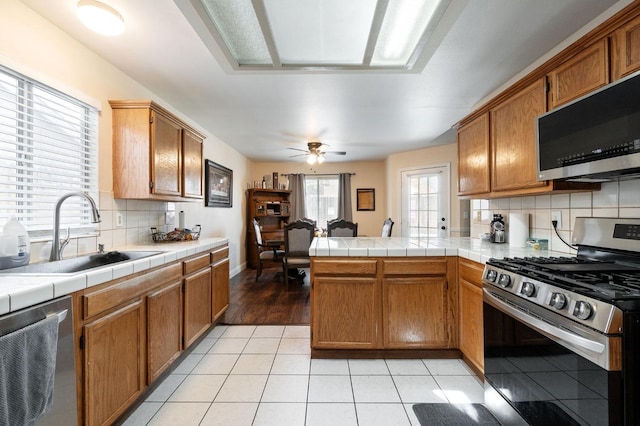 kitchen with tile counters, sink, appliances with stainless steel finishes, and tasteful backsplash