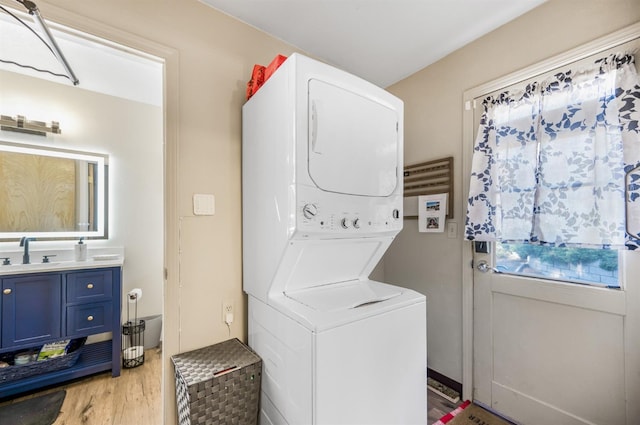 laundry room featuring light hardwood / wood-style floors, sink, and stacked washer and dryer