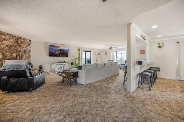 living room featuring a textured ceiling, carpet floors, ceiling fan, and crown molding