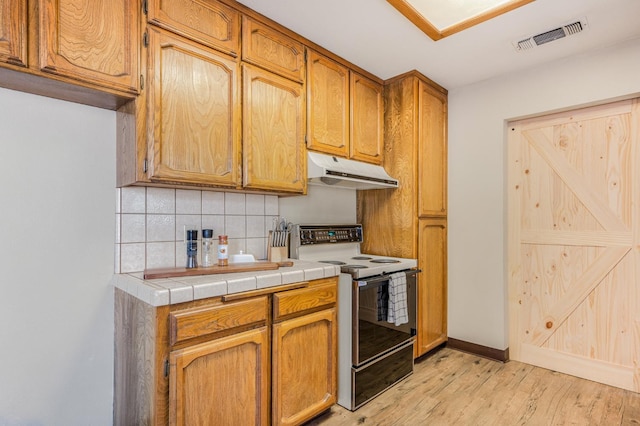 kitchen with backsplash, white range with electric cooktop, tile counters, and light hardwood / wood-style flooring