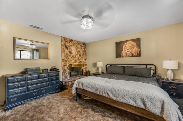 carpeted bedroom featuring a fireplace and ceiling fan