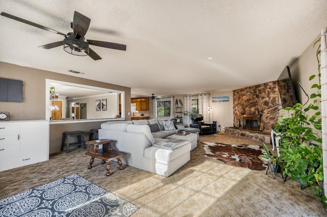 carpeted living room with ceiling fan, a fireplace, and a textured ceiling