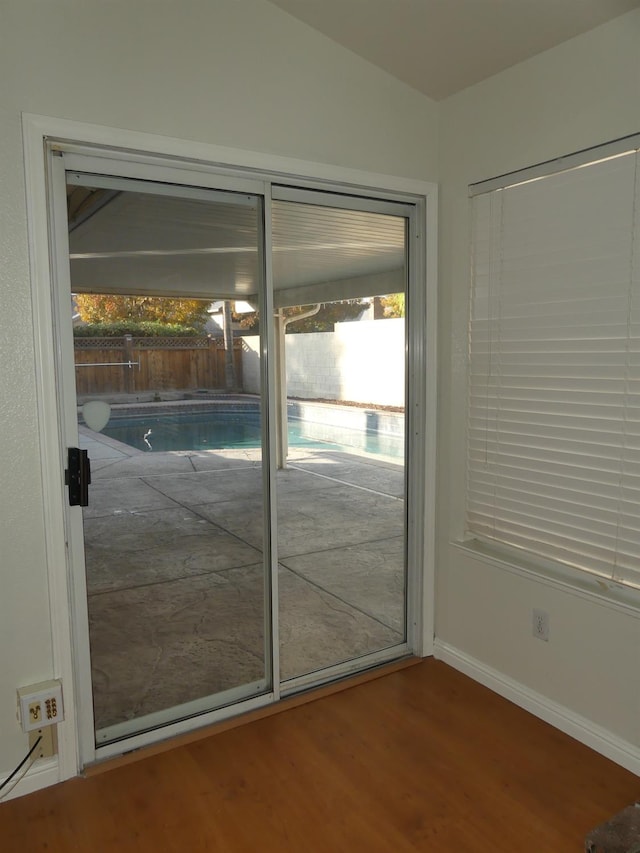 doorway with hardwood / wood-style floors and vaulted ceiling