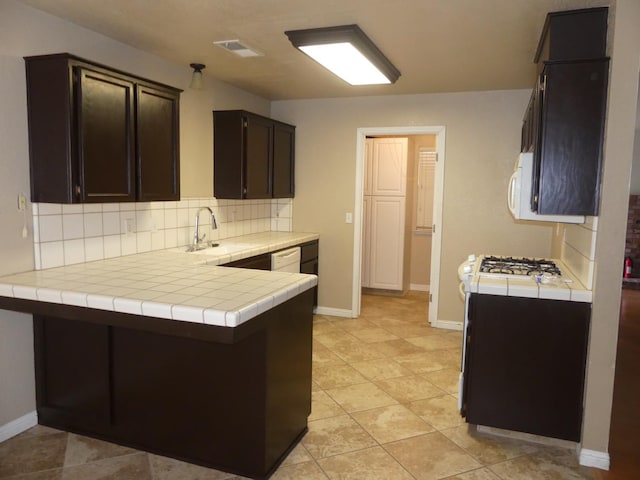 kitchen featuring tile counters, sink, kitchen peninsula, decorative backsplash, and dark brown cabinets