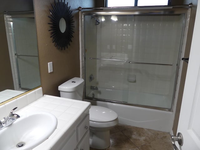 full bathroom with shower / bath combination with glass door, tile patterned flooring, vanity, and toilet