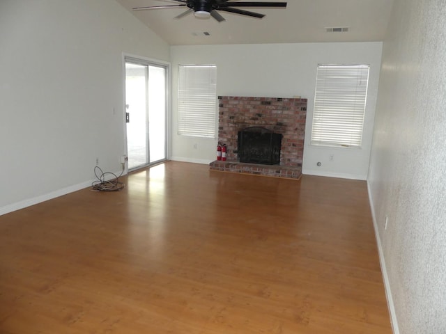 unfurnished living room featuring a fireplace, lofted ceiling, hardwood / wood-style flooring, and a healthy amount of sunlight