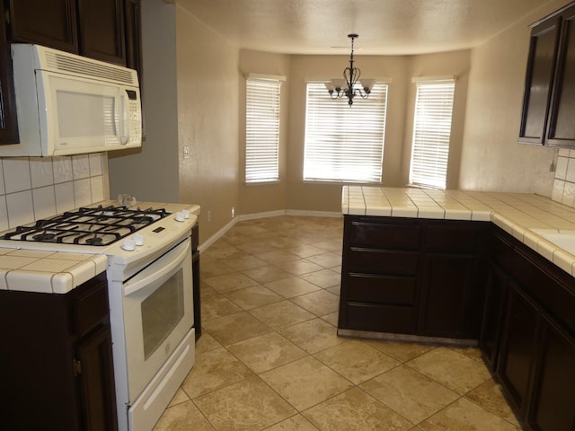 kitchen featuring white appliances, tile countertops, and backsplash