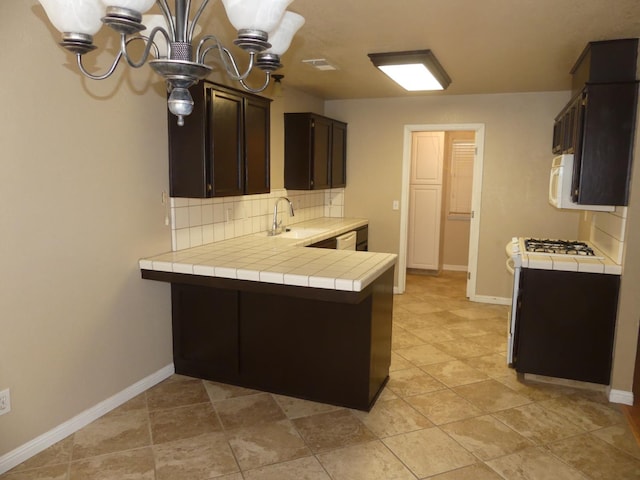 kitchen with white appliances, backsplash, sink, dark brown cabinets, and kitchen peninsula