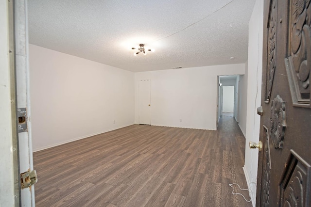 unfurnished room with dark hardwood / wood-style floors and a textured ceiling