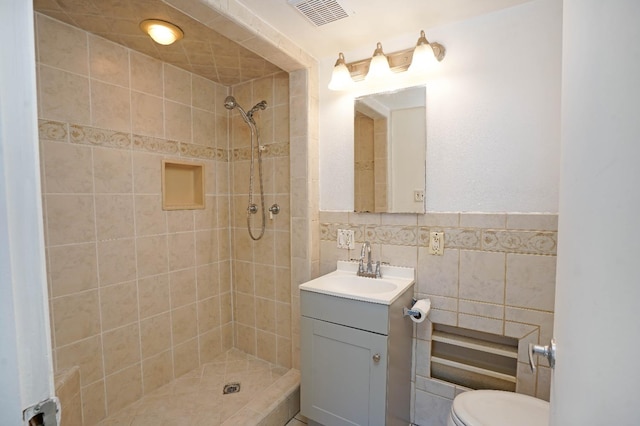 bathroom featuring toilet, vanity, tile walls, and tiled shower