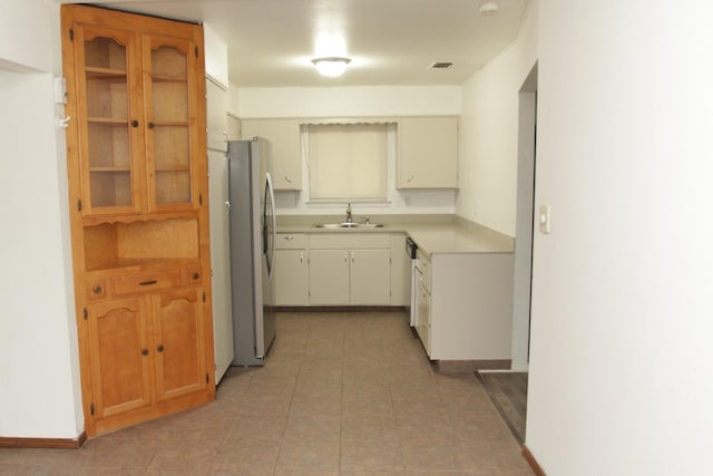 kitchen with white cabinets, sink, and stainless steel refrigerator