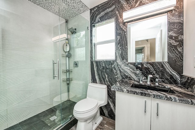 bathroom with vanity, toilet, tile walls, and walk in shower