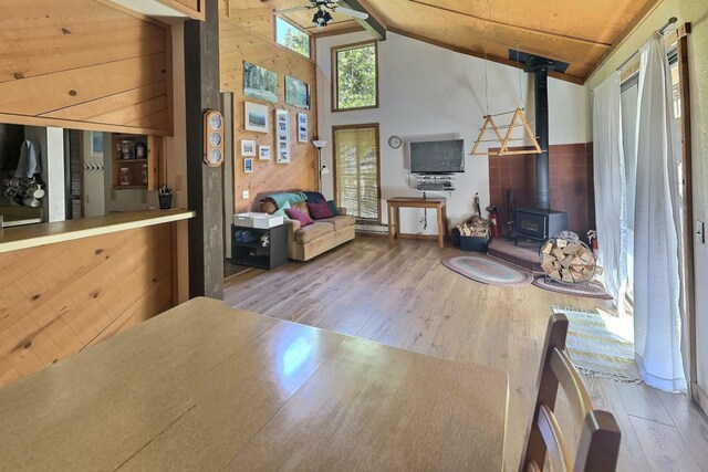 living room with lofted ceiling, a wood stove, hardwood / wood-style flooring, ceiling fan, and wood ceiling