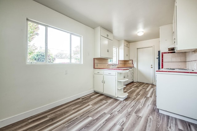 kitchen featuring light hardwood / wood-style floors, white cabinetry, backsplash, and range