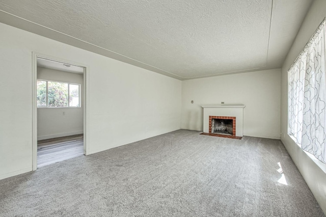 unfurnished living room with a fireplace, carpet, and a textured ceiling