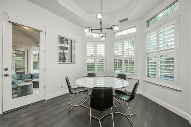 dining area featuring a raised ceiling, a healthy amount of sunlight, dark hardwood / wood-style floors, and a notable chandelier