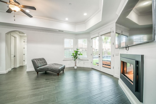 sitting room with a raised ceiling, crown molding, dark hardwood / wood-style flooring, and ceiling fan