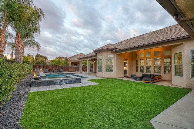 back of house featuring a yard, a swimming pool with hot tub, a patio, and an outdoor hangout area