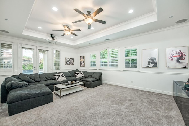 living room featuring a tray ceiling, ceiling fan, crown molding, and carpet floors