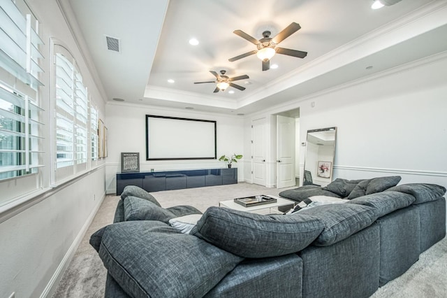 carpeted home theater featuring ceiling fan, ornamental molding, and a tray ceiling