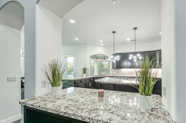 kitchen with backsplash, light stone countertops, a center island, and pendant lighting