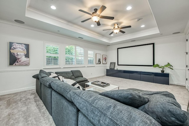 carpeted cinema room featuring a raised ceiling, ceiling fan, and ornamental molding