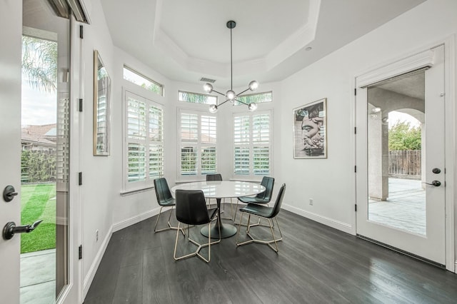 dining area featuring a chandelier, dark hardwood / wood-style floors, and a raised ceiling