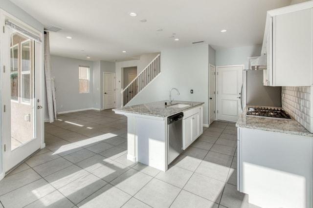 kitchen featuring white cabinets, stainless steel appliances, a wealth of natural light, and an island with sink