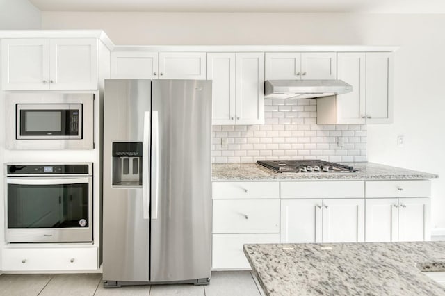 kitchen with light tile patterned flooring, stainless steel appliances, white cabinetry, and light stone counters