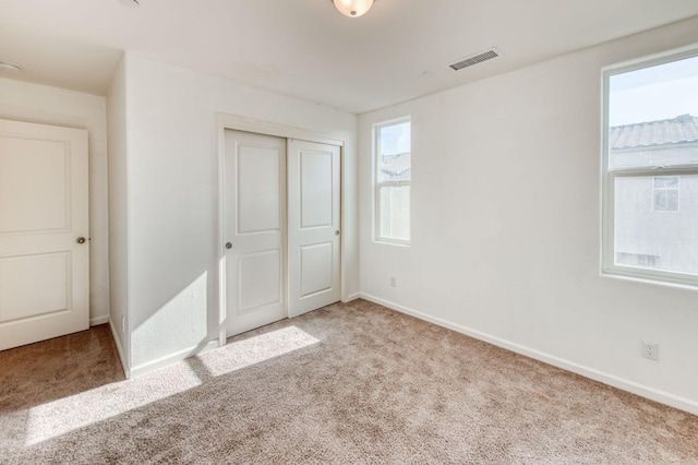 unfurnished bedroom featuring a closet, light colored carpet, and multiple windows