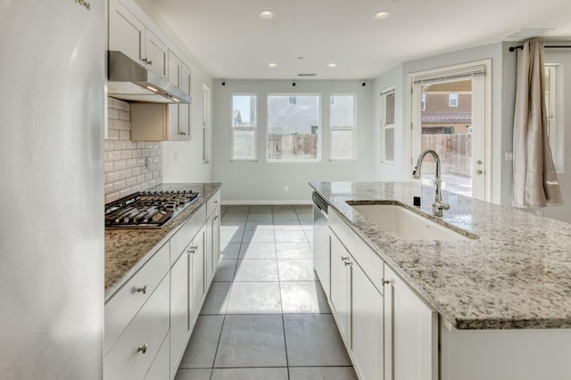 kitchen with a kitchen island with sink, white cabinets, sink, appliances with stainless steel finishes, and tasteful backsplash