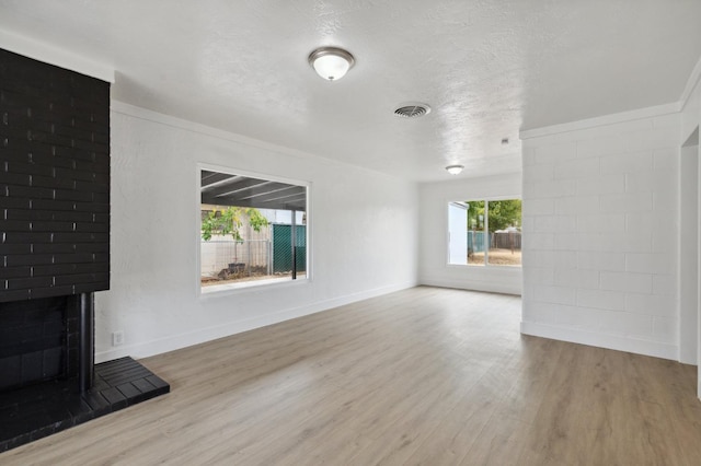 unfurnished living room featuring a fireplace, light hardwood / wood-style flooring, and a textured ceiling