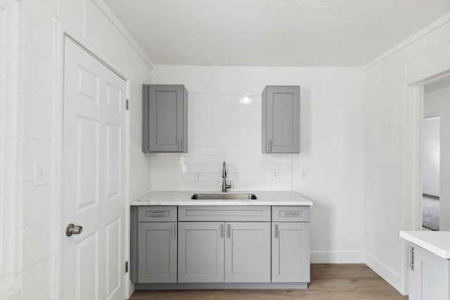 kitchen featuring gray cabinets, light hardwood / wood-style flooring, tasteful backsplash, and sink