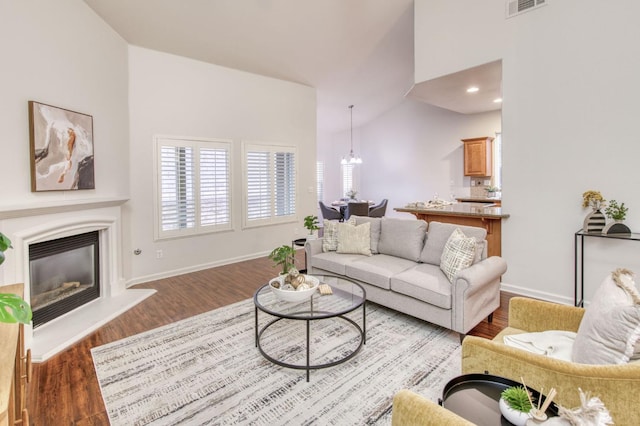 living room featuring dark hardwood / wood-style flooring, vaulted ceiling, and a notable chandelier