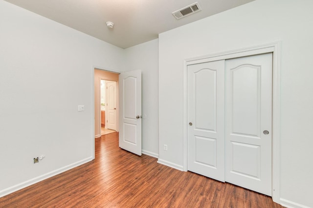 unfurnished bedroom featuring dark hardwood / wood-style floors and a closet