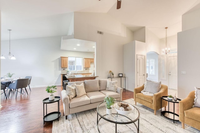 living room featuring an inviting chandelier, high vaulted ceiling, and light wood-type flooring