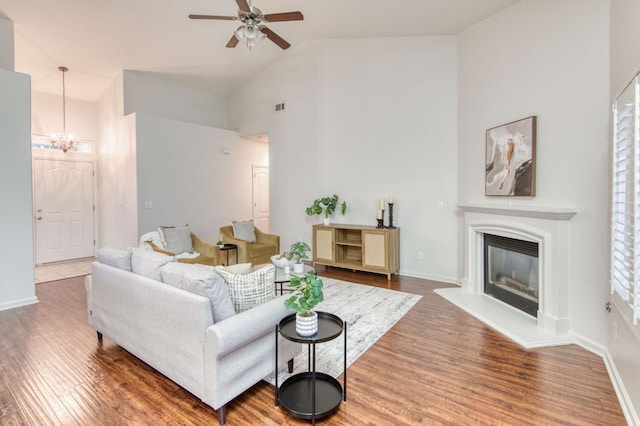 living room featuring lofted ceiling, hardwood / wood-style floors, and ceiling fan with notable chandelier