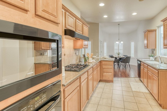 kitchen with pendant lighting, sink, light tile patterned floors, black appliances, and light stone countertops