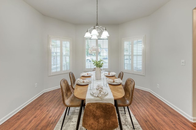 dining area with dark wood-type flooring and a chandelier