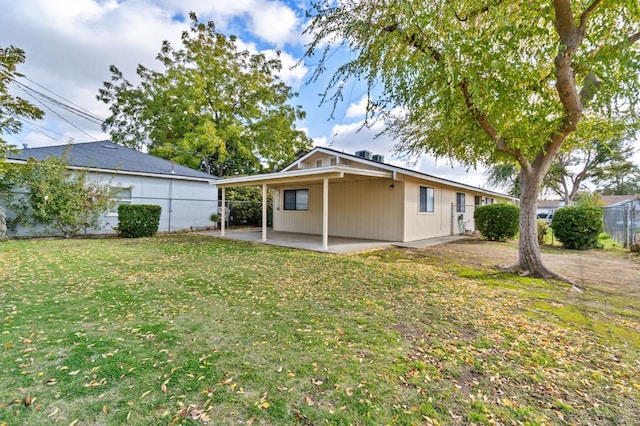 rear view of house featuring a patio, an attached carport, fence, and a yard