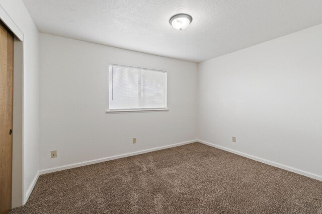 carpeted spare room featuring baseboards and a textured ceiling