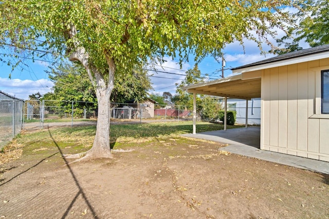 view of yard with an attached carport, a gate, and fence