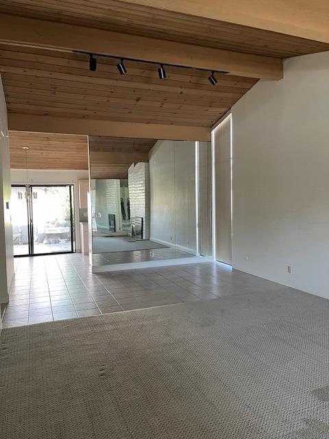 interior space with beam ceiling, wooden ceiling, tile patterned flooring, a notable chandelier, and track lighting