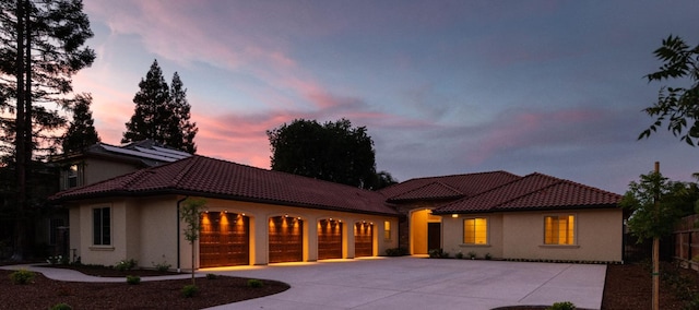 mediterranean / spanish-style house featuring stucco siding, concrete driveway, an attached garage, and a tile roof