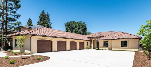 mediterranean / spanish home with stucco siding, concrete driveway, a tile roof, and a garage