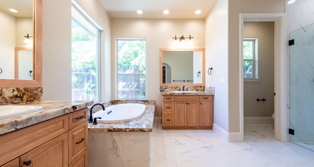 full bath with a garden tub, two vanities, marble finish floor, and a sink